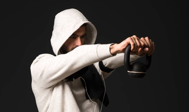 Sport man over dark background making weightlifting - Φωτογραφία, εικόνα