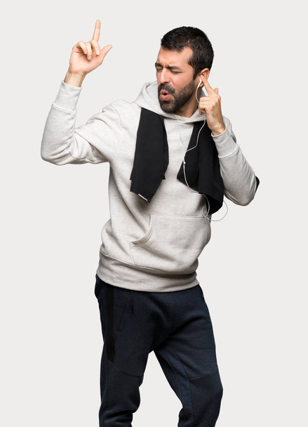 Sport man luisteren naar muziek met een koptelefoon en dansen op geïsoleerde grijze achtergrond - Foto, afbeelding
