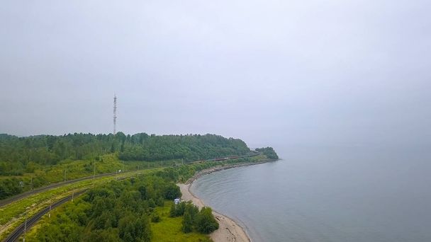 Russia, Baikal - 02 agosto 2018: Trans-Siberian Railway, coast of Lake Baikal. Movimento del treno lungo la riva del lago, Da Drone
  - Foto, immagini