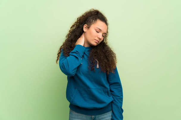 Teenager girl over green wall with neckache - Fotografie, Obrázek