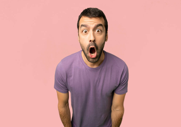 schöner Mann mit überraschung und schockiertem Gesichtsausdruck auf isoliertem rosa Hintergrund - Foto, Bild