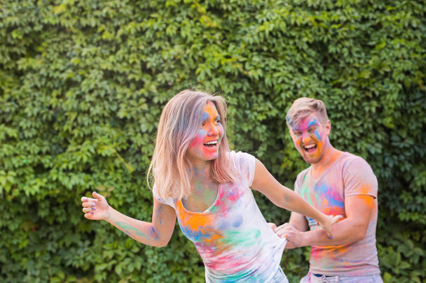 Friendship, festival of holi, people concept - young couple playing with colors at the festival of holi - Фото, изображение