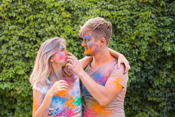 Dovolená, holi a lidé koncept - šťastný pár se baví s vícebarevné prášek na jejich tvářích - Fotografie, Obrázek