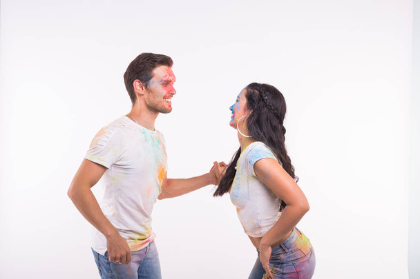Holiday, social dance, holi and people concept - Happy couple having fun covered in paint and dancing bachata or kizomba on white background - Photo, Image