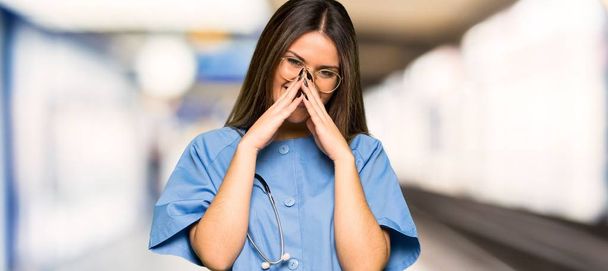 Enfermera joven sonriendo mucho mientras cubre la boca en un hospital
 - Foto, imagen