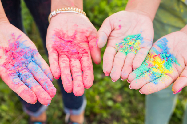 Holiday, festival holi and family concept - Palms of young people covered in different colors over nature background - 写真・画像