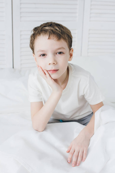 Cute boy woke up in the morning and sleepy sitting in bed  - Photo, image