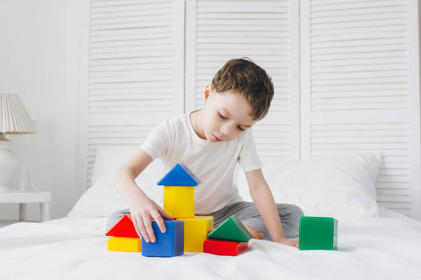 Boy plays and builds a tower of colorful plastic cubes  - Φωτογραφία, εικόνα