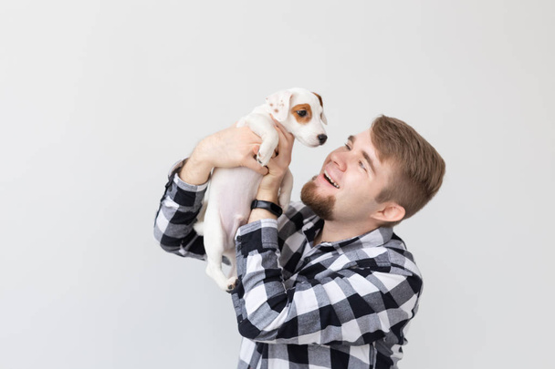 people, pets and animals concept - close up of young man holding jack russell terrier puppy on white background - Photo, Image