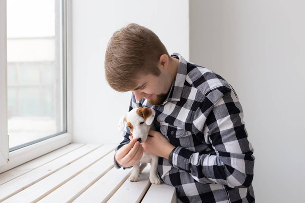 Άνθρωποι, κατοικίδιο και σκυλί ιδέα-νεαρός άντρας πάνω από το παράθυρο κρατώντας το κουτάβι Τζακ Ράσελ τεριέ - Φωτογραφία, εικόνα