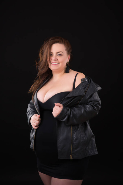 Mooie jonge vrouw plus grootte met grote buste in ondergoed en Leather Jacket n zwarte achtergrond - Foto, afbeelding