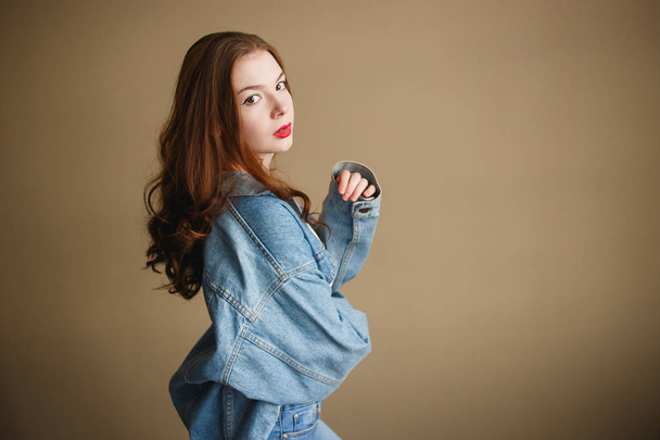 Fiatal Nő Modell Pózol Denim kabát bézs háttér. Vissza az 1990-es évekhez Fashion Lifestyle Style Concept - Fotó, kép