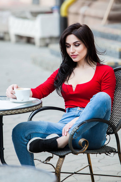 街でのコーヒーのカップを持つ豪華な若い女性。コーヒー ブレーク。スタイリッシュな流行に敏感な女の子が通りにコーヒーを飲みます。コーヒーを飲みながら美しい少女のアウトドア ファッション ポートレート. - 写真・画像
