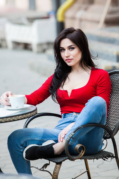 Prachtige jonge vrouw met kopje koffie in de stad straat. Koffiepauze. Stijlvolle hipster meisje drinken koffie in de straat. Openlucht mode portret van jong mooi meisje koffie drinken. - Foto, afbeelding