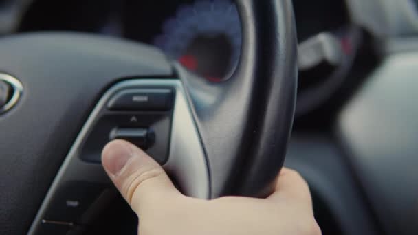 車の運転手は舵のスイッチを使用して、トリップコンピュータの調整を変更しています - 映像、動画