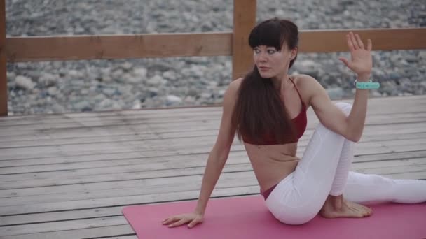 Sportswoman yoga eğitimi üzerinde sırt ve bacaklar kaslar ve tendonlar germe - Video, Çekim