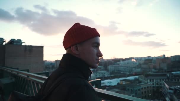 Young man admiring the view from the terrace at sunset - Materiał filmowy, wideo