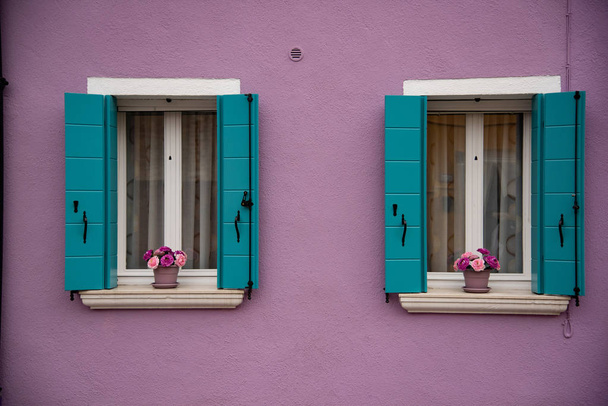 Detalhe das janelas e porta pintada colorida, ilha de Burano, Veneza, Veneto, Itália, Europa. Panelas de flores cor-de-rosa no peitoril da janela, persianas verdes, janela branca
 - Foto, Imagem