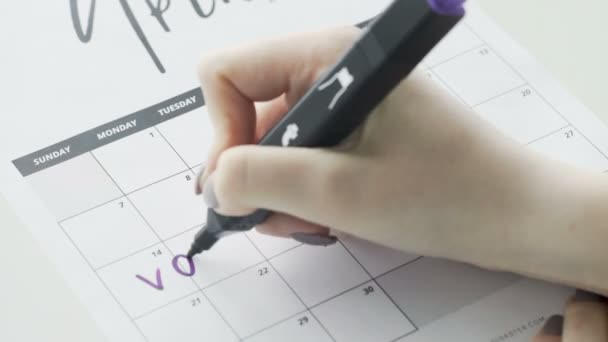 Womans hand writing with Violet felt pen on calendar word vacation - Footage, Video