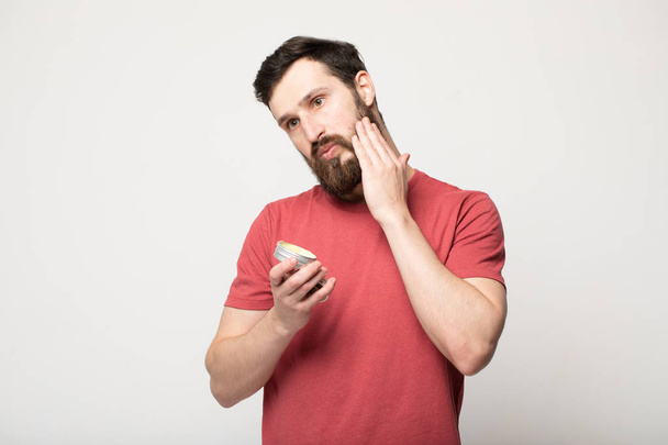 Close-up image of handsome bearded man holding beard balm. - Foto, Imagen
