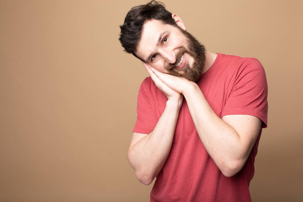 Close-up portrait of his he nice attractive handsome calm bearded guy wearing checked t-shirt showing sleeping gesture isolated over beige pastel background - Fotoğraf, Görsel