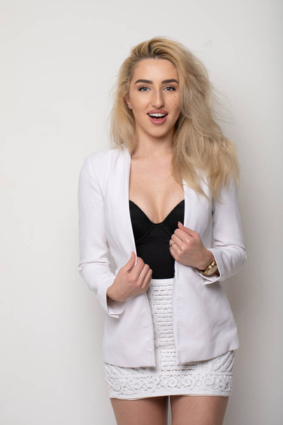 Studio portrait of attractive caucasian woman with blonde hair in white suit grey background. Bossy female, confident independent lady - Zdjęcie, obraz