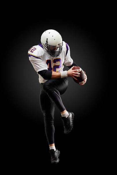 Giocatore di football americano in un salto con una palla su uno sfondo nero
 - Foto, immagini