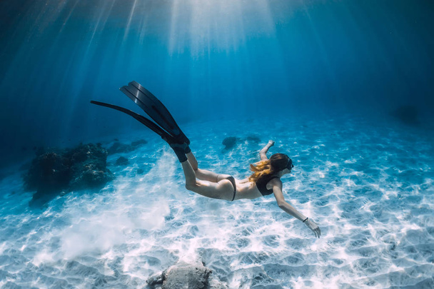 Mujer liberadora con aletas nadando sobre fondo arenoso. Freediving submarino en Hawaii
 - Foto, imagen