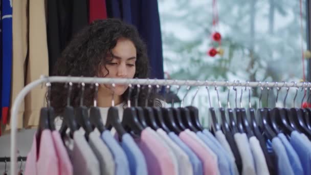 Odběratel ženy si prohlíží zboží na stojanu v obchodě s oděvy v době prodeje - Záběry, video