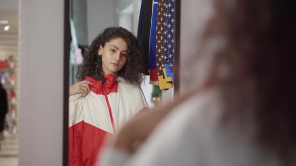 Jeune femme regarde miroir, appliquer à elle-même deux vestes dans le magasin
 - Séquence, vidéo