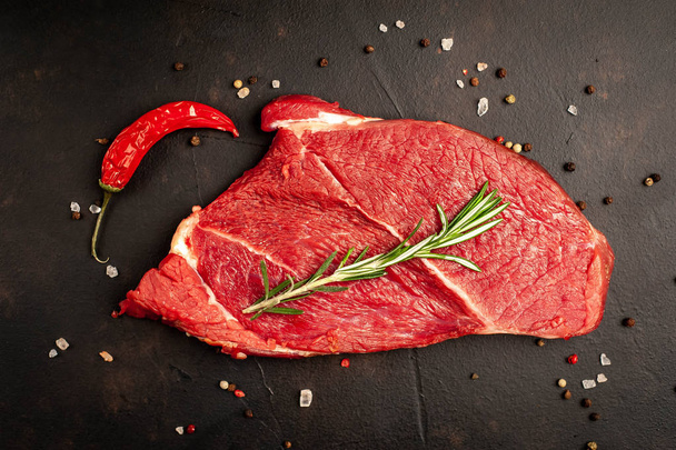 Un gros steak new-yorkais cru aux ingrédients. sur le fond de pierre sombre
. - Photo, image