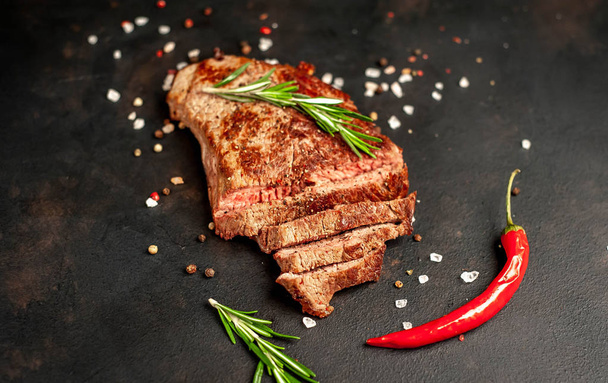 Ready-to-eat steak of New York black angus beef breeds with ingredients on a concrete background. Ready meal for dinner on a dark stone background - Фото, зображення