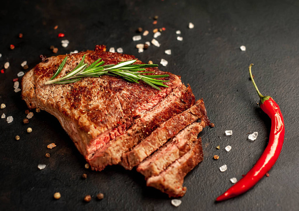Ready-to-eat steak of New York black angus beef breeds with ingredients on a concrete background. Ready meal for dinner on a dark stone background - 写真・画像