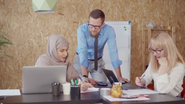 Mężczyzna, blond i muzułmańska kobieta omawiają na powierzchni biurowej w dzień roboczy - Materiał filmowy, wideo