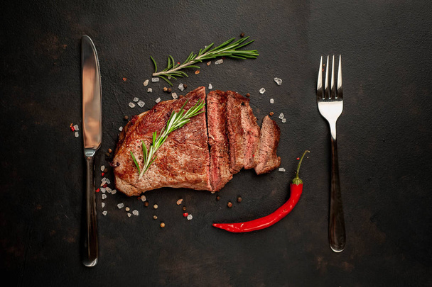 Ready-to-eat-Steak von New York Black Angus Beef Rassen mit Zutaten auf einem Betongrund. Fertiggericht zum Abendessen auf dunklem Steinhintergrund - Foto, Bild