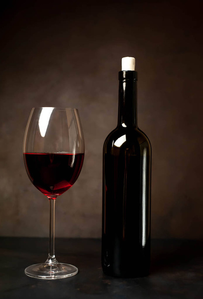 Wine glass with red wine and bottle against a stone background.  - Fotografie, Obrázek