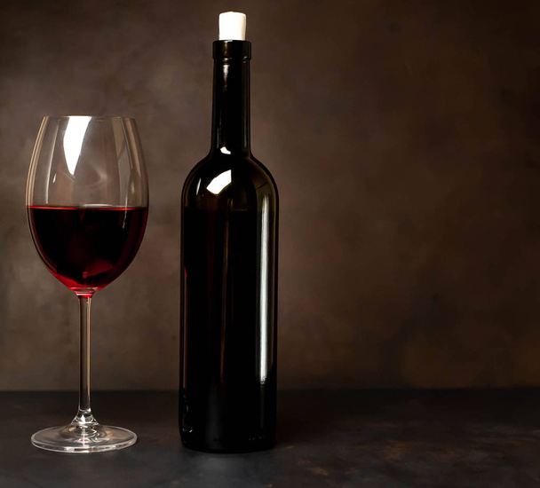 Ποτήρι κρασιού με κόκκινο κρασί και ένα μπουκάλι με ένα πέτρινο φόντο.  - Φωτογραφία, εικόνα