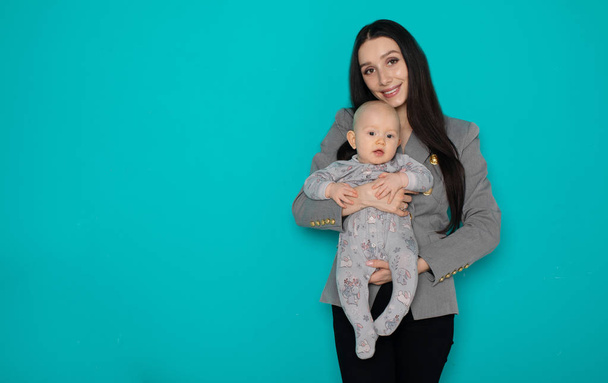 Young mother holding her newborn child. Woman and new born boy relax on color background. Mother breast feeding baby. Family at home. Young mother playing with her newborn son - Fotó, kép