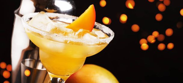 Mango daiquiri, alcoholic cocktail with white rum, liqueur, syrup, lemon juice, mango and ice on black bar counter background, copy space, selective focus - Foto, afbeelding