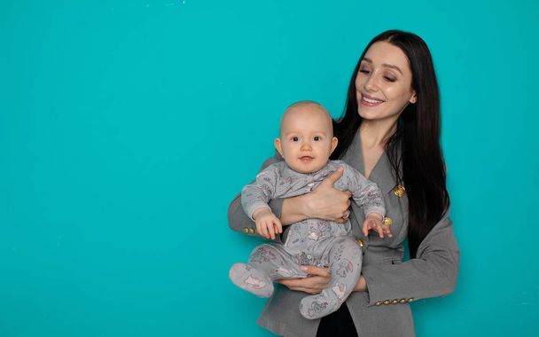 Young mother holding her newborn child. Woman and new born boy relax on color background. Mother breast feeding baby. Family at home. Young mother playing with her newborn son - Foto, afbeelding