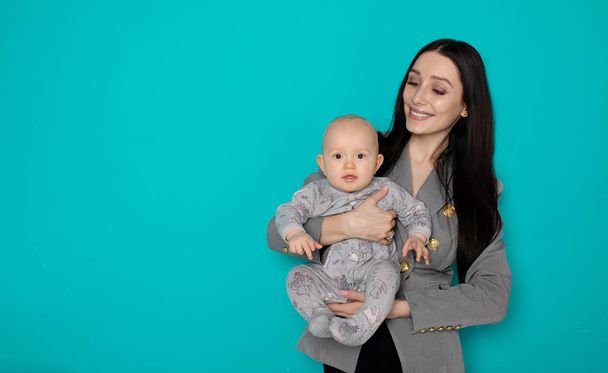 Young mother holding her newborn child. Woman and new born boy relax on color background. Mother breast feeding baby. Family at home. Young mother playing with her newborn son - Zdjęcie, obraz