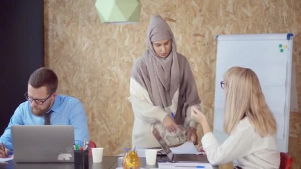 Arabska i kaukaski kobieta dyskutują i biorą papier w nowoczesnym biurze - Materiał filmowy, wideo