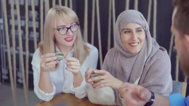 Людина розмовляє з двома арабськими і кавказькими жінками смішні розповіді в кафе - Кадри, відео