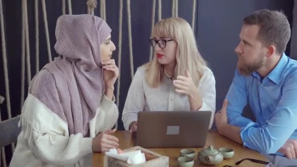 zwei Frauen und ein Mann diskutieren im Raum und schauen auf den Bildschirm des Laptops - Filmmaterial, Video