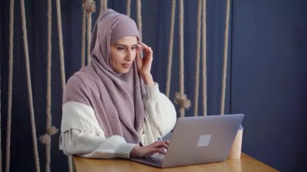 Mulher muçulmana está digitando mensagens no laptop no café, descansando sozinho
 - Filmagem, Vídeo