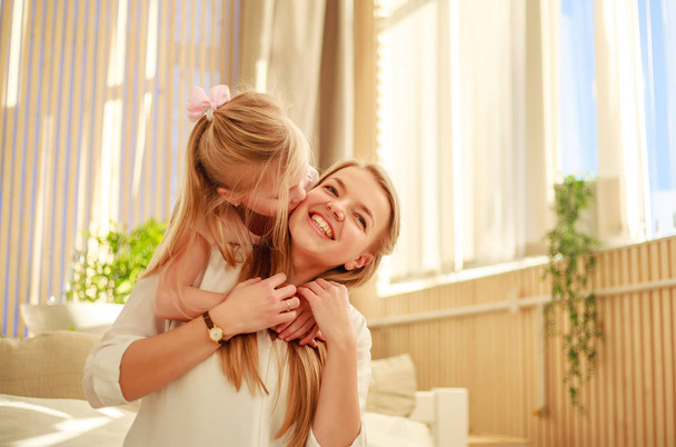 Mother and daughter joyfully hugging at home on bed - Foto, Imagem