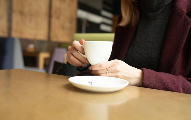 Close up of beautiful female hands holding big white cup of cappuccino coffee. - 写真・画像