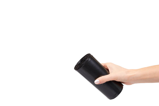 hand with roll of black plastic garbage bags for trash - Foto, afbeelding