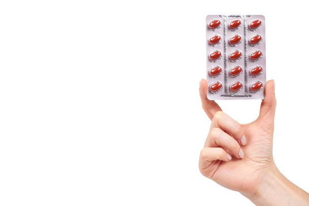 punainen vitamiinikapseli läpipainopakkauksessa, jossa on käsi, lääkedupplement
 - Valokuva, kuva
