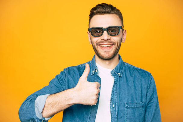 I'm chilling. A man near the yellow background with his thumb pointed up which tells about his cool mood as well as the smile over his face. - Foto, imagen